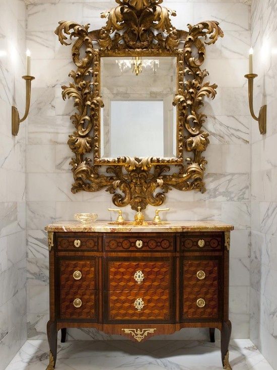 Золотое резное зеркало на фоне белого мрамора с прожилками