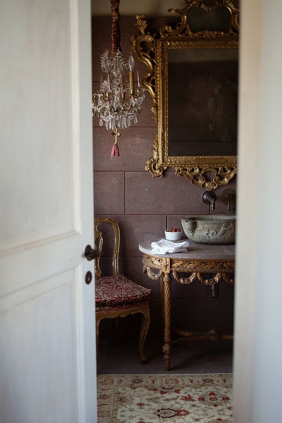 интерьер ванной комнаты с каменной мойкой на консоли и золотым зеркалом