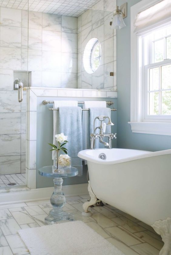 Интерьер голубой ванной комнаты с окном в классике